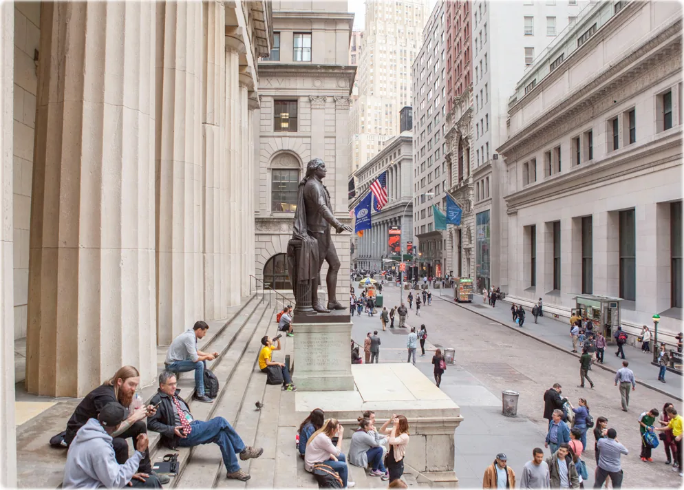 Wall Street financial district street scene with people outside a historic building.